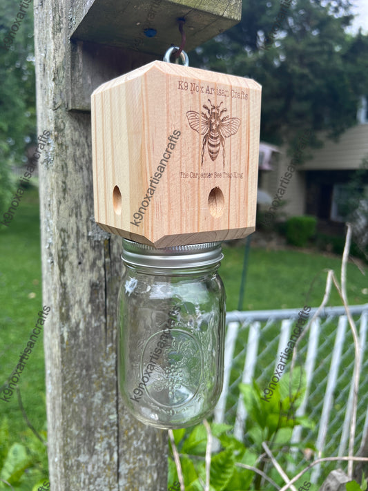 Wooden bee house with a Mason jar attached to a wooden post outdoors.